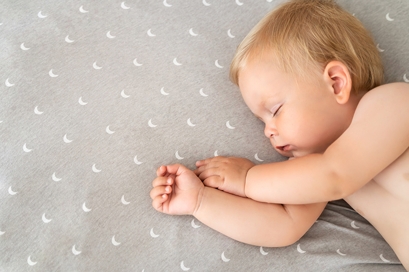 Closeup of baby sleeping in bed watching sweet dreams after active play in bedroom