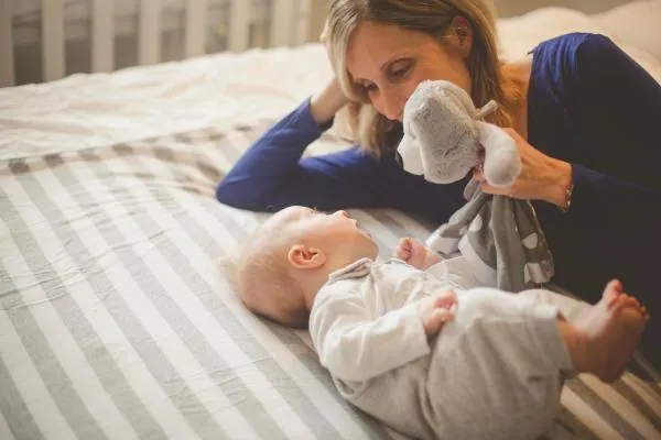 A mother and her baby staring at a toy its mother is holding