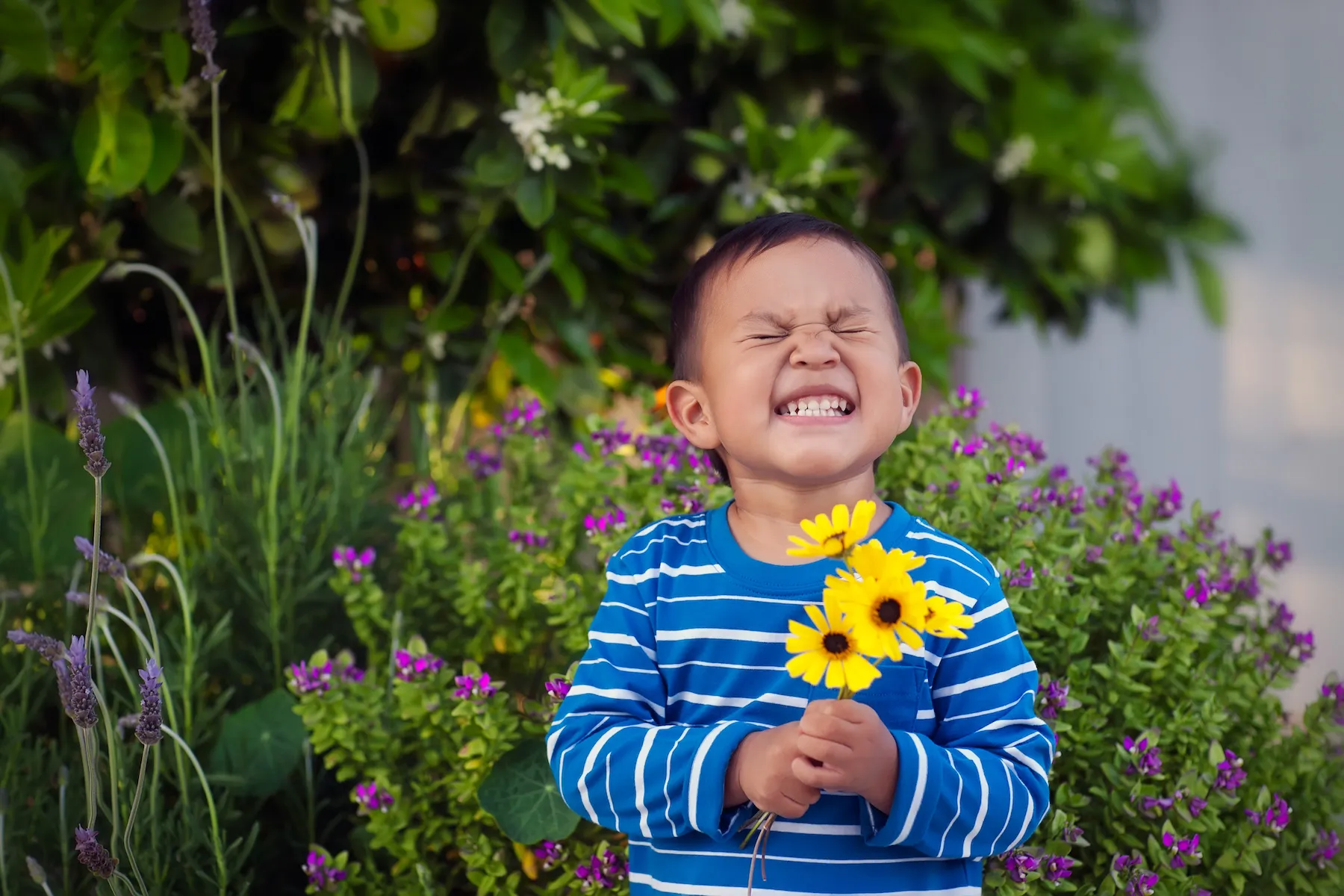 A happy boy holding a bunch of flowers